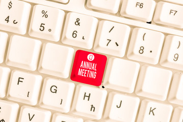 Conceptual hand writing showing Annual Meeting. Concept meaning yearly meeting of the general membership of an organization White pc keyboard with note paper above the white background