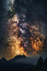 Milky Way galaxy in Universe astrophotography. Silhouettes of mountains and trees. Stars and nebula at night sky landscape