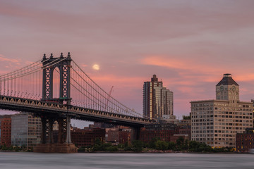 Manhattan bridge from east river at sunset with full moon rise