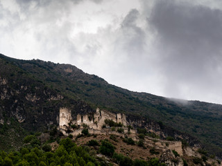 Fototapeta na wymiar castillo templario en ruinas en lo alto de una colina rodeado de montañas con cielo nublado 
