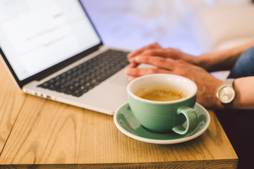 Closeup business woman hands using laptop with cup coffee. Woman Hands Typing keyboard computer In Coffee Shop. smartphone and hot cup Cappuccino in table. People lifestyles concept. Freelance theme
