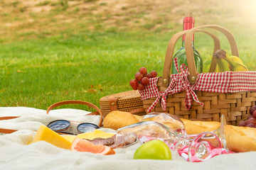 Picnic, camping basket, wine, glasses and fruits, family picnic background with space. Summer and mood. Weekend and vacation, sunny mood