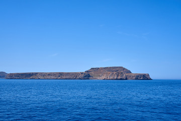 Fototapeta na wymiar Rocky islands near Crete, Greece, with clear sky on a background and blue sea on a foreground. Copy space.