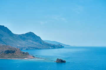 Fototapeta premium Rocky islands near Crete, Greece, with clear sky on a background and blue sea on a foreground. Copy space.