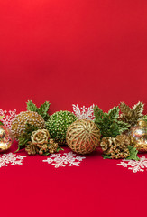 Golden, green, white Xmas decorative balls, snowflakes, flowers on red background for greeting card design with free space for text