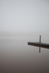 Empty boat dock on lake, on a foggy winter morning