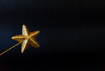 Christmas golden star magiс wand with glitter isolated closeup on black background, template for...