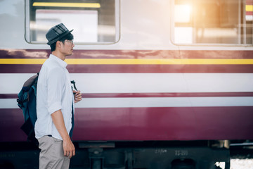 Asian man is traveler, he is waiting for their train. Outdoor adventure travel by train concept. Bangkok, Thailand. Happy/positive/healthy hike/travel/wanderlust concept