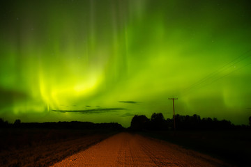 Beautiful northern lights over a gravel road in a nighttime Canadian landscape