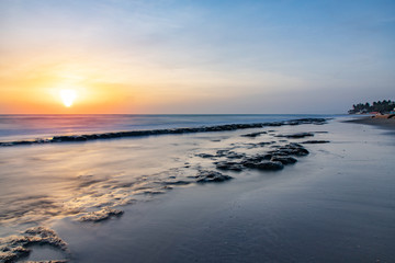 Fototapeta na wymiar Seascape horizon with rocks in the water and ocean waves at sunrise on Cabarete beach, Dominican Republic