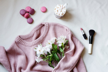 Flat lay composition. Knitted woolen sweater pink color, cup of coffee with marshmallow , macaroon...