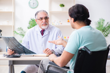 Fototapeta premium Male patient in wheel-chair visiting old doctor
