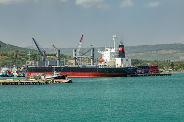 Fototapeta premium Ships, vessels, boats, containers, industrial buildings at the Puerto Plata harbor, port and cityscape, Dominican Republic
