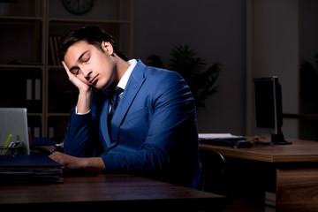 Young male employee working night in the office