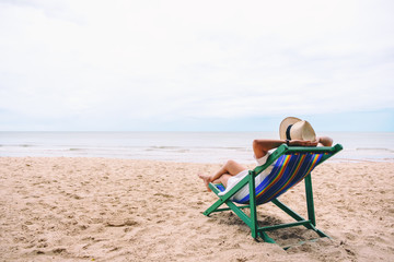 Fototapeta na wymiar A woman lying down on a beach chair with feeling relaxed