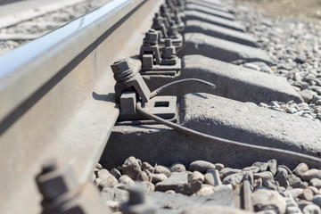 Close-up of the screws on the rail for the train. The sleepers and the two tracks in the distance span into each other