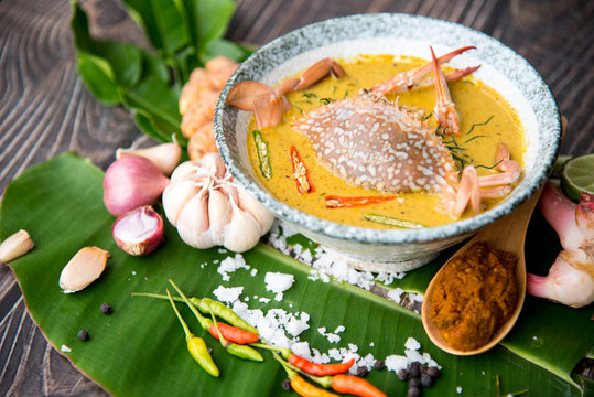 Crab meat coconut milk curry, in bowl and ingredient of Thai Red curry paste on brown wooden background Thai food / Select focus image, thai food concept.