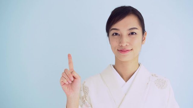 Japanese Kimono woman pointing, against light blue background