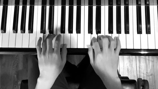 Young positive boy playing piano in black and white.