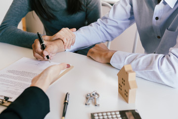 Salesmen are letting the male customers sign the sales contract house, Asian women and couple are doing business in the office , Business concept and contract signing