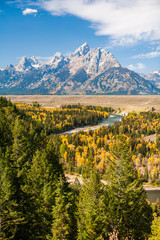 Grand Teton Mountain Range forms the background of the Snake River and fall colors of a grove of...