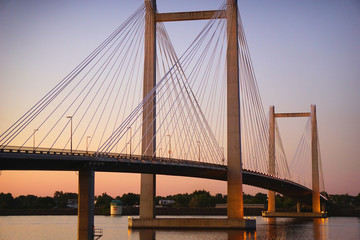 Cable suspension bridge over river at dusk