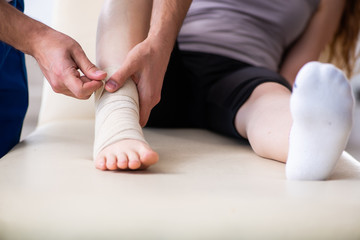 Obraz na płótnie Canvas Leg injured woman visiting young doctor traumatologist