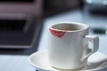 Lipstik mark on cup, white cup of coffee on table, woman desk