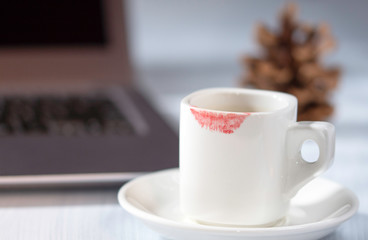 Lipstick mark on cup, white cup of coffee on table, woman desk
