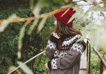 Beautiful carefree long hair asian girl in the red hat and knitted nordic sweater in autumn nature park, travel adventure lifestyle