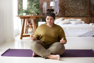 Young woman meditating at home, making mudra gesture