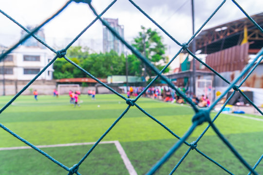 Kid Is Training Soccer Football In Blur Background Behind The Net