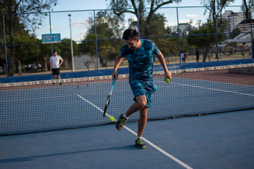 Hombre adulto latino con barba de camiseta azul en pantaloneta jugando tenis  con amigo en cancha...