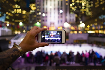 Fototapeta na wymiar A tourist is taking pictures with his phone at the Rockefeller tower in New York, USA. Rockefeller Plaza is an American Art Deco skyscraper.