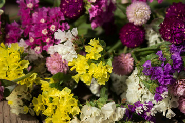 Gomphrena globosa and Limonium - beautiful pink, yellow and white summer flowers on wooden background in the garden
