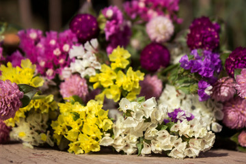 Gomphrena globosa and Limonium - beautiful pink, yellow and white summer flowers on wooden background in the garden