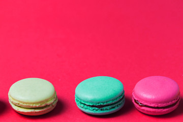 Close up of baked three multicolored macaroons on pink background