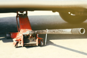 Car Lifted With Red Hydraulic Floor Jack selective focus