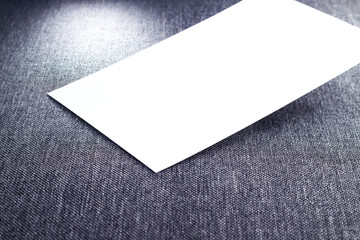 Blank paper, white empty business card, poster or flyer on gray fabric texture. Blank signboard with copy space area for text or slogan