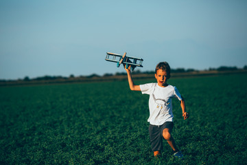 Fototapeta premium cute boy playing with toy airplane outdoor in meadow