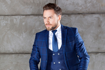 portrait of young handsome man wearing blue suit and tie, hair style, beard. Studio shot
