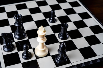 Chess king standing wins the game of chess setup on dark background. Chess concept save the king and save the strategy, game over.