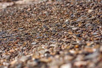 Sea pebble - beautiful gravel beach in sunlight, blurred background