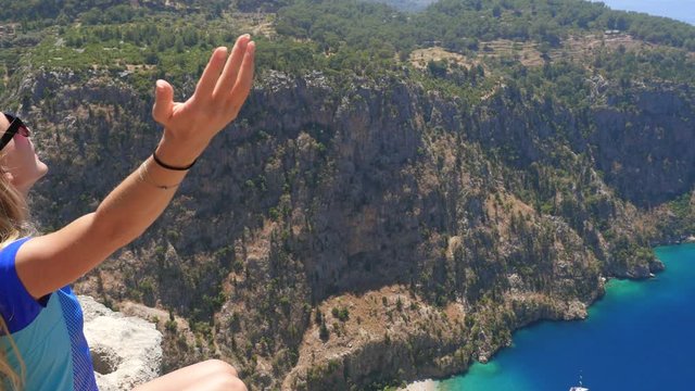 Young woman enjoying freedom and taking sun bath with beatiful viewn of Butterfly Valley on background in Turkey