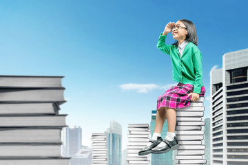 Asian cute girl with glasses sitting on the pile of books and looking forward