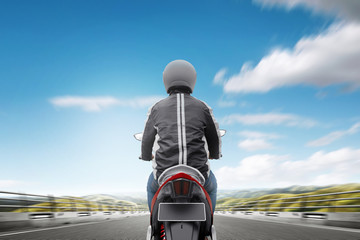 Rear view of Asian motorcycle taxi man driving on the asphalt road
