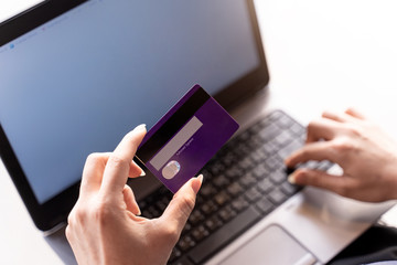 Woman holding credit card and typing on the keyboard of laptop with Shopping cart, online shopping, online payment.