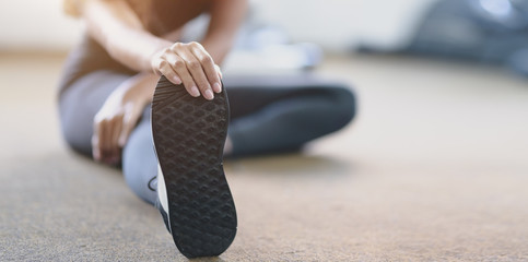 Close-up view of woman with tan and slim body stretching legs before exercise