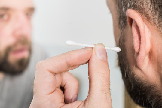 Man removing wax from ear using Q-tip