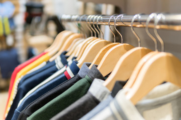 Fototapeta premium Fashion clothes on clothing rack - bright colorful closet. Closeup of rainbow color choice of trendy male wear on hangers in store closet